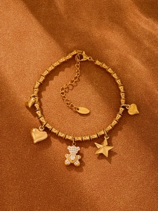 Detail eines goldenen Bambusketten-Armbands mit Bär-, Herz- und Sternanhängern aus Edelstahl