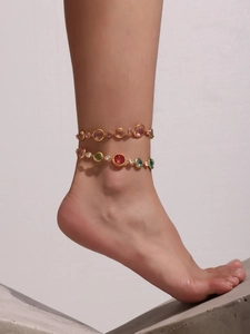 Detail of double-layer gold anklet featuring vibrant multi-colored round gemstones