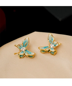 Macro shot of gold butterfly earrings with blue-green enamel and marquise zircon on silk