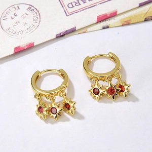 Detail of gold hoop earrings with three red star pendants on vintage letter paper