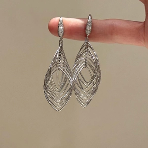 Silver layered hollow leaf earrings with sparkling zircon studs on a warm background