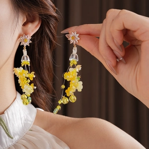 Détail de boucles d'oreilles à fleurs avec zircons jaunes et perles sur un modèle