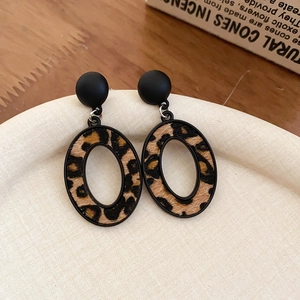 Détail de boucles d'oreilles léopard en similicuir avec clou noir mat sur plateau