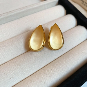 Vista macro degli orecchini a goccia placcati in oro 18k con finitura spazzolata