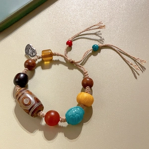 Detail of handmade bracelet with Dzi bead, turquoise turtle and silver Fu pendant