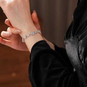 Close-up of zircon and chalcedony flower bracelet worn by a model on a dark sleeve