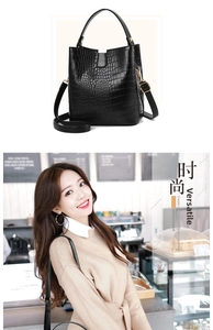 Detail of black crocodile texture bucket bag with gold hardware and long shoulder strap
