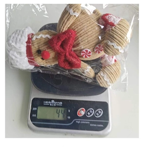 Weight display of gingerbread man plush pendant in packaging on a digital scale