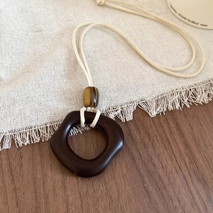 Detailed close-up of a resin square pendant on a wax cord over a linen texture