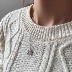 Detailed view of silver leaf texture rectangular pendant on a fine chain over a knit sweater