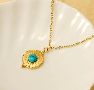 Macro shot of gold sunburst pendant with turquoise stone inlay on a white shell