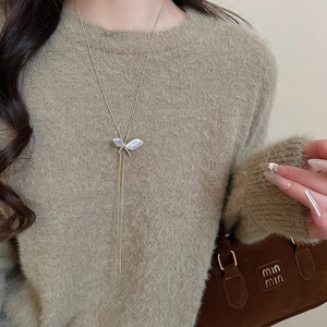 Detailed view of butterfly pendant with pearl and rhinestones on soft sweater