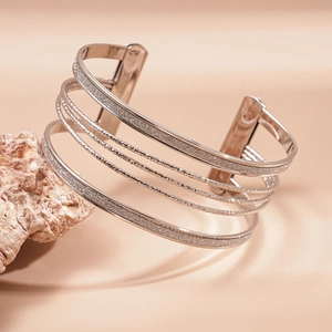 Close-up of layered silver geometric bracelet with glitter texture on natural stone