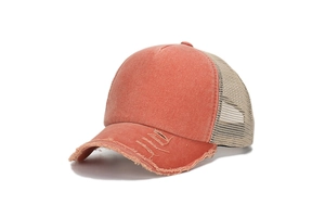 Detail of distressed orange trucker hat featuring breathable mesh and frayed brim design