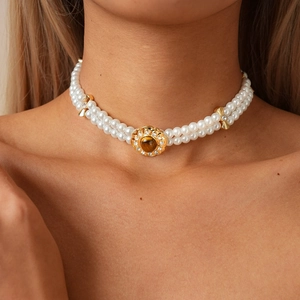 Close-up of double-layer pearl necklace with a gold flower buckle and tiger eye stone
