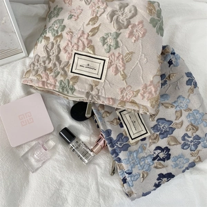 Texture de broderie détaillée sur trousse de maquillage fleurie avec fermeture éclair