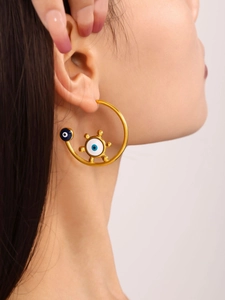 Detail of gold-plated hoop earrings featuring blue evil eye charms on a female model