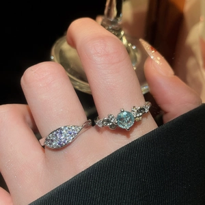 Macro shot of sparkling blue gemstone ring and leaf-shaped silver band with cubic zirconia