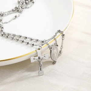 Detail of a 6mm silver stainless steel rosary necklace with crucifix on a porcelain dish
