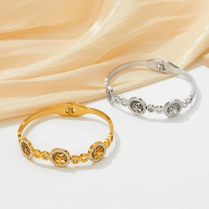 Gold and silver Tree of Life hollow cuff bracelets with cubic zirconia on silk background