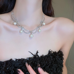 Close-up of layered silver necklace with pearls and rhinestones on model neck