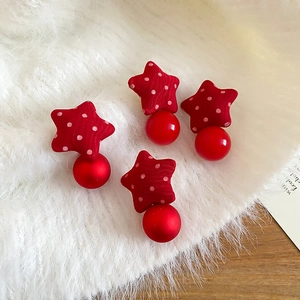 Detail of red polka dot fabric star earrings with beads on white faux fur background