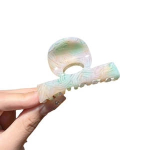 Elegant acetate marble pattern hair claw clip with French lettering on white background