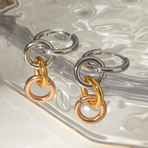 Détail de boucles d'oreilles créoles tricolores entrelacées en argent, or et or rose poli