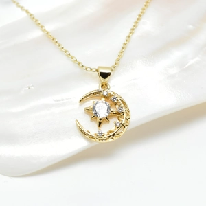 Macro view of 18k gold star and moon pendant with shimmering white zircon stones