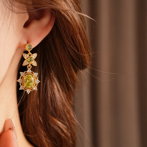 Gros plan de boucles d'oreilles vintage en or avec gemme verte ovale et oxydes de zircon