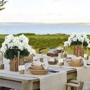 Artificial white begonia flowers in rustic wooden pot for elegant outdoor table setting
