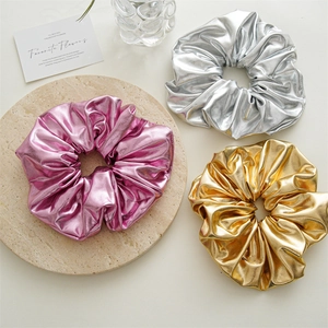 Detail of metallic textured oversized scrunchies in pink, silver and gold finishes