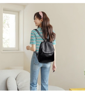 Elegant black leather anti-theft backpack for women shown on model in a home setting