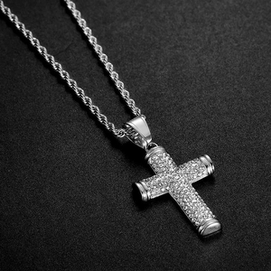 Silver hip hop necklace with iced out rhinestone cross pendant on black texture background