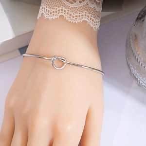 Close-up of minimalist silver knot bracelet showing polished metal texture on wrist