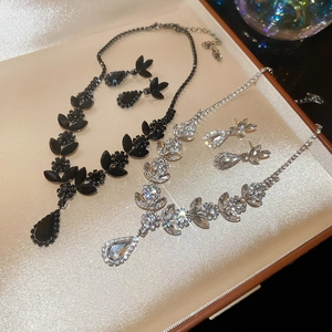 Macro detail of wheat ear pendant necklace and earrings set with teardrop crystals