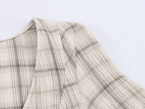 Detailaufnahme einer hellgrauen karierten Baumwollbluse mit Kragen und Schulternaht-Details
