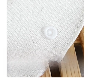 Close-up of white plastic snap button on a textured fabric canvas shoulder bag