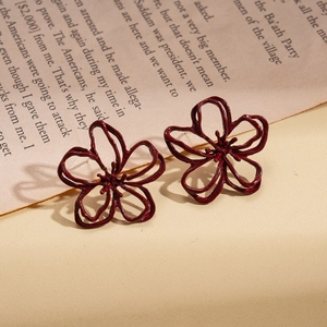 Gros plan de boucles d'oreilles fleurs rouges sur papier vintage et fond chaud