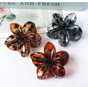 Three flower-shaped resin hair claws in amber and smokey grey colors with metal springs