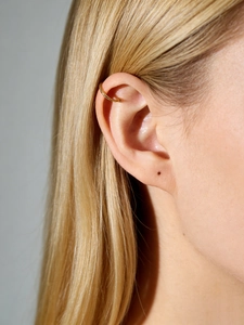 Close-up of a minimalist golden C-shaped ear cuff worn on the upper ear cartilage