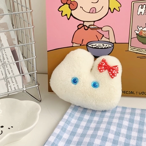 Detail of white plush bunny keychain with red polka dot bow and blue eyes on a plaid cloth