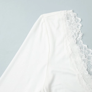 Gros plan sur la bordure en dentelle blanche et le tissu en maille douce du col en V