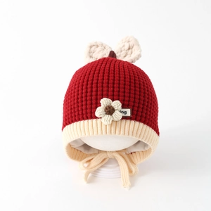 Detailed close-up of knit baby hat with floral accents, plush lining and ear flaps