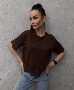 Detalle de blusa marrón de manga corta con elegantes bordados de encaje en mangas y dobladillo
