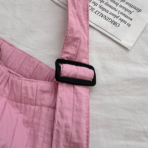Detail of pink pleated canvas strap with a black plastic adjustable buckle for shoulder bags