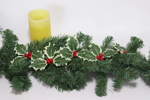 Detail view of artificial pine needles, green holly leaves and red berries for Christmas decor