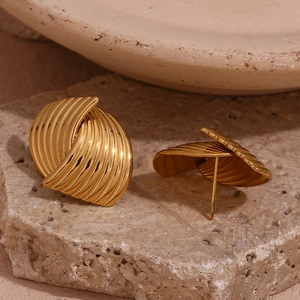 Macro view of 18K gold plated fan-shaped earrings with textured geometric stripes