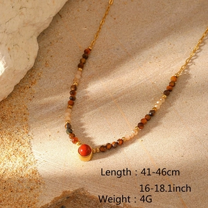 Detail of layered titanium steel necklace with natural colorful stone beads on sand