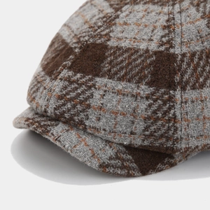 Detail shot of brown and grey plaid newsboy cap showing wool blend texture and stitching